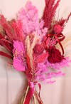 Dried flower bouquet in deep red and pink tones set against a plain backdrop. Valentines Day Dried Flower Bouquet.