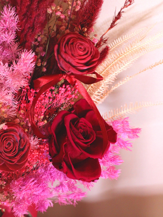 Close up photo of a preserved red rose amongst other dried flowers. The photo shows details of a dried flower bouquet for Valentine's day. 