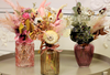 three different small vases filled with dried flowers in grey table