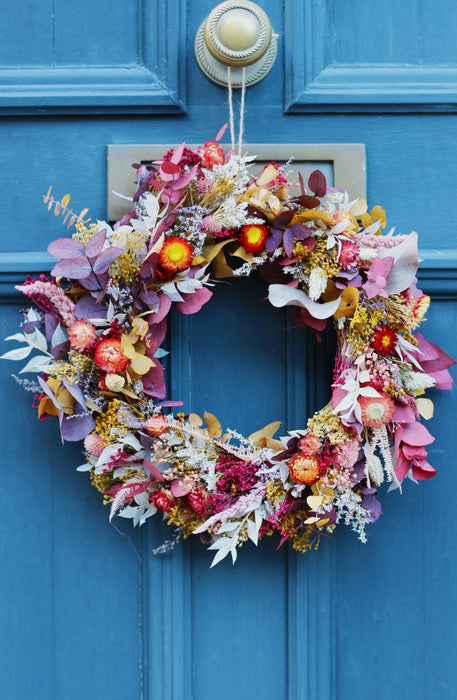 Beautiful flowers in a mixed dried flower wreath against a blue door background