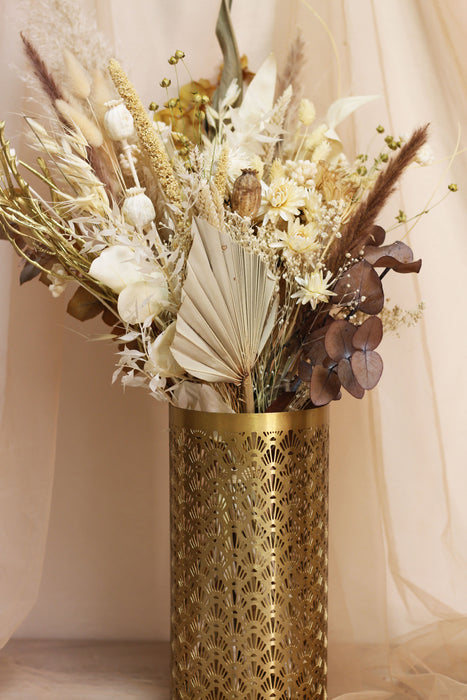 Autumn Moonrise dried flower bouquet of mixed pale flowers in gold vase against light peach background 