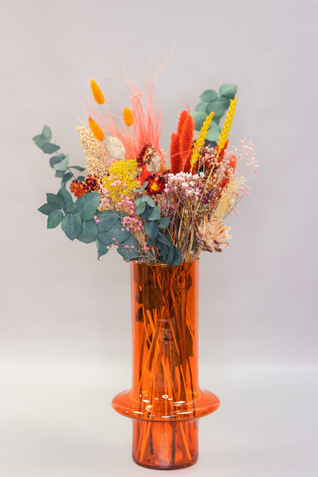 selection of colorful dried flowers in tall clear glass vase, paprika colour